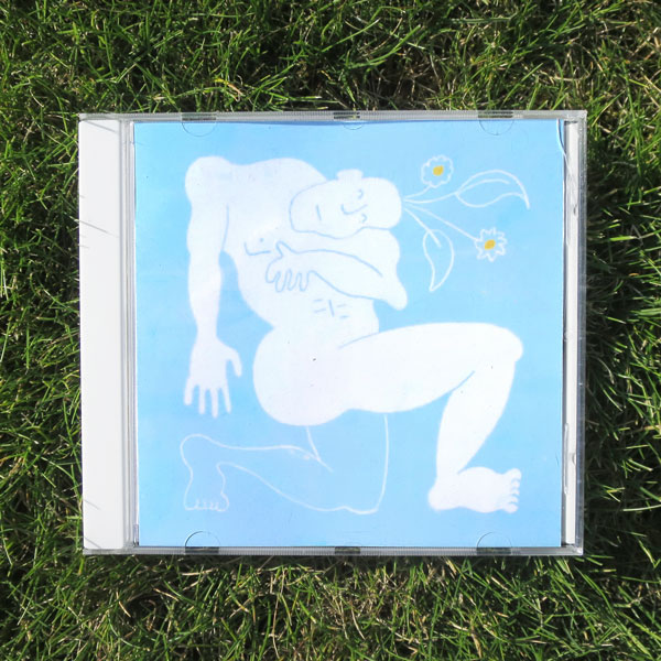 A photo of a CD in the grass. The cover depicts a contorted drawn figure, with flowers coming out the top of his head.